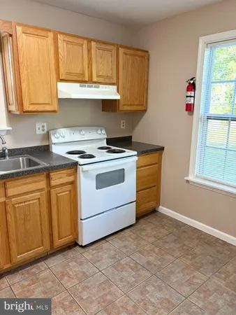 a kitchen with granite countertop a stove a sink and a white cabinets