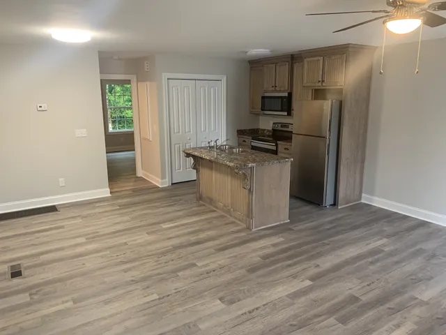 a kitchen with granite countertop a refrigerator and a stove top oven