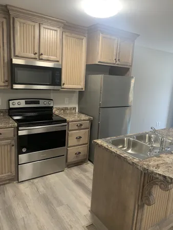 a kitchen with granite countertop a sink stove and refrigerator