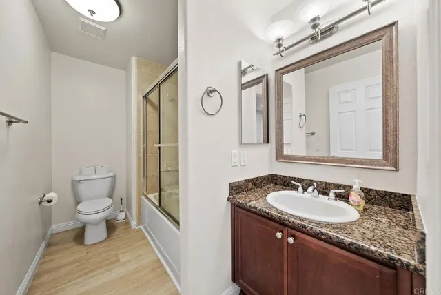 a bathroom with a granite countertop sink a toilet and a mirror