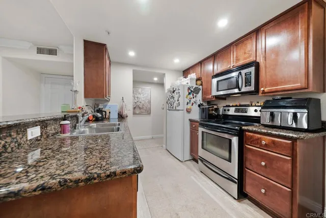 a kitchen with stainless steel appliances granite countertop a stove a sink and a microwave
