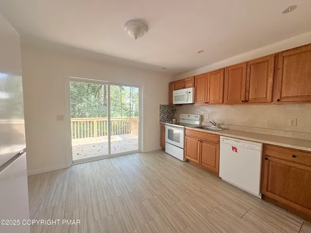 a kitchen with stainless steel appliances granite countertop a stove a sink dishwasher and white cabinets with wooden floor