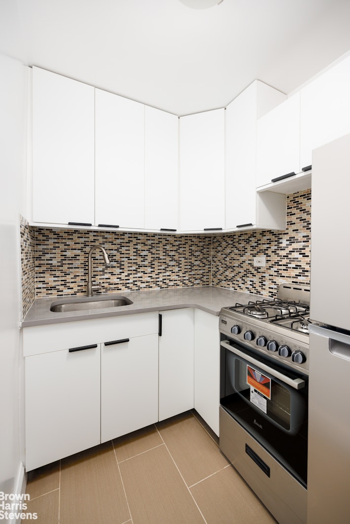 520 East 81st Street, Unit 5A Manhattan, NY 10028 - Photo 7 of 9 a kitchen with granite countertop a stove sink and cabinets