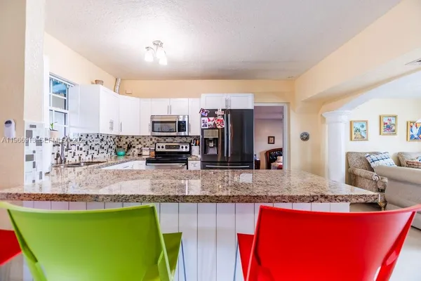 a large kitchen with stainless steel appliances granite countertop a granite counter tops and a view of living room