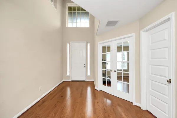 an empty room with wooden floor and windows
