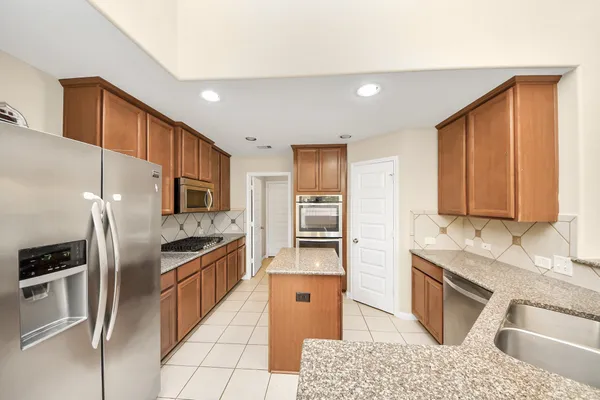 a kitchen with stainless steel appliances granite countertop a refrigerator a stove and sink