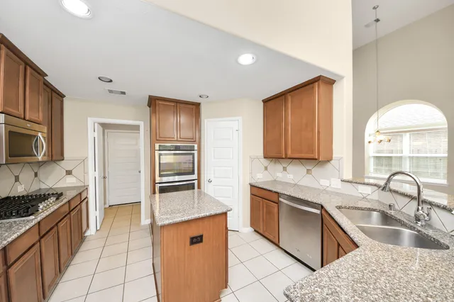 a kitchen with stainless steel appliances granite countertop a sink stove and refrigerator