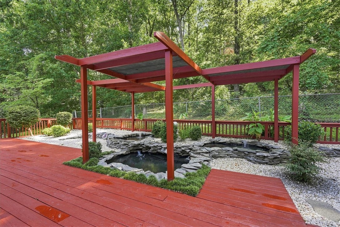 1052 Madden Bridge Road Central, SC 29630 - Photo 41 of 50 An inviting wooden deck frames a custom stone pond feature nestled beneath a red pergola.