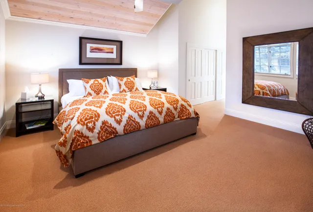 a bed sitting in a bedroom next to a window with a large mirror