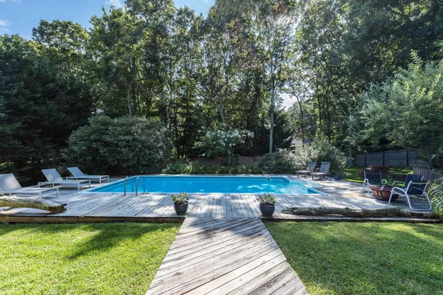 a view of swimming pool with seating space and trees in the background
