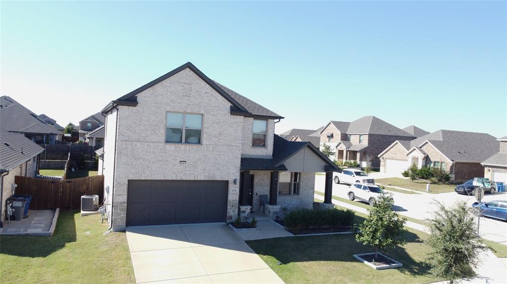 View of front facade with a residential view, driveway, brick, and an attached garage