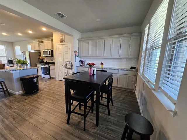a kitchen with a dining table chairs and refrigerator
