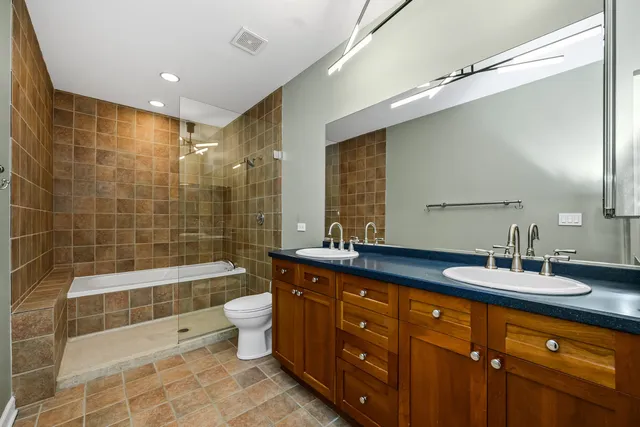 a bathroom with a double vanity sink a toilet a mirror and shower