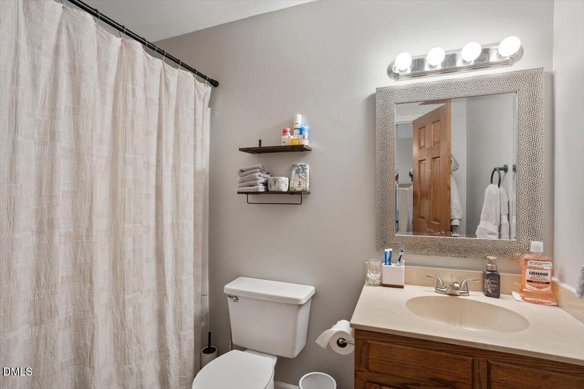 5442 Sharpe Drive Raleigh, NC 27612 - Photo 12 of 20 a bathroom with a toilet a sink and a mirror