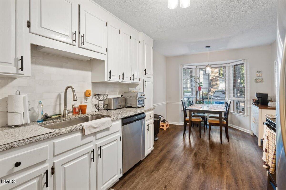 5442 Sharpe Drive Raleigh, NC 27612 - Photo 3 of 20 a kitchen with granite countertop a stove a sink a dining table and chairs