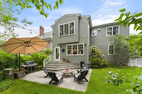 a backyard of a house with table and chairs under an umbrella