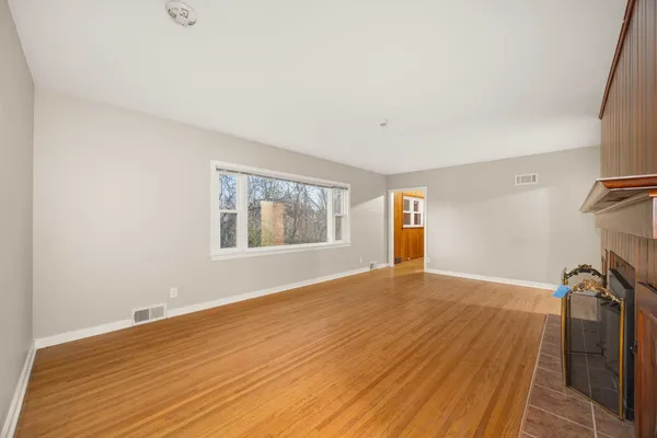 a view of empty room with wooden floor and fan