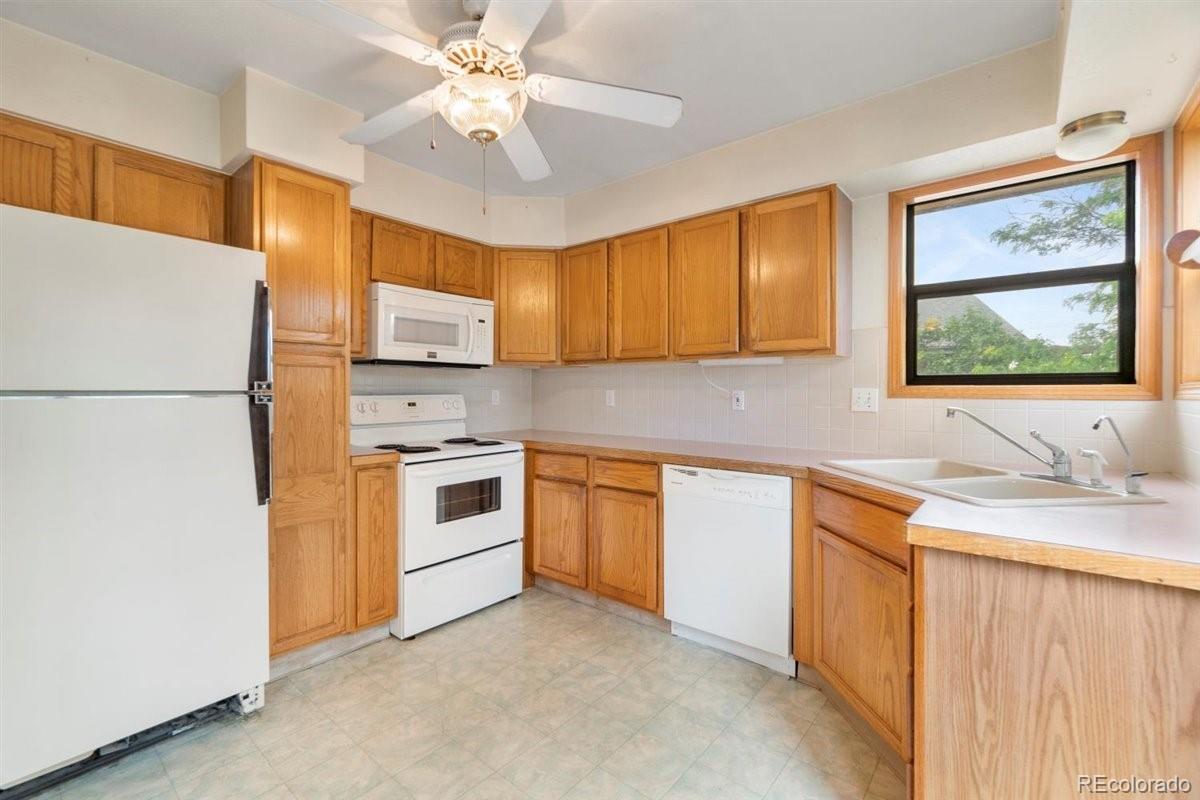 833 Wade Road Longmont, CO 80503 - Photo 13 of 40 a kitchen with stainless steel appliances granite countertop a stove a sink a refrigerator a microwave oven with cabinets and wooden floor