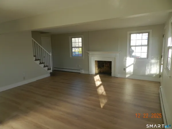 a view of empty room with fireplace and wooden floor