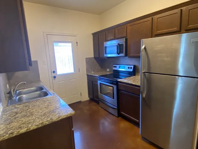 a kitchen with stainless steel appliances granite countertop a refrigerator stove and sink