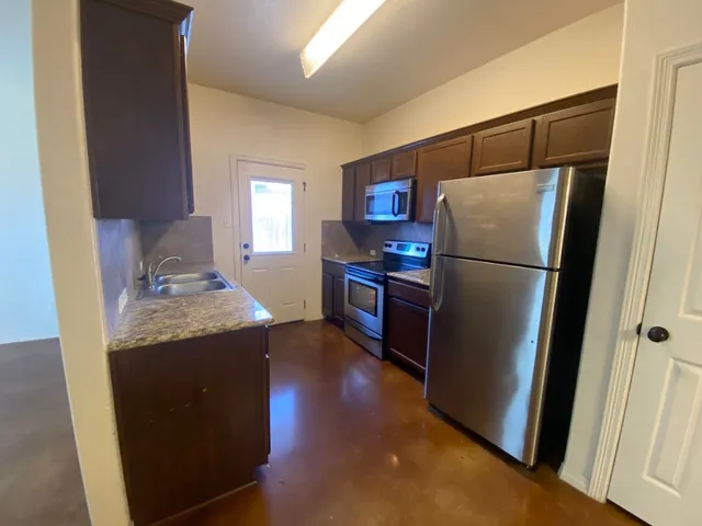 a kitchen with granite countertop a refrigerator and a sink
