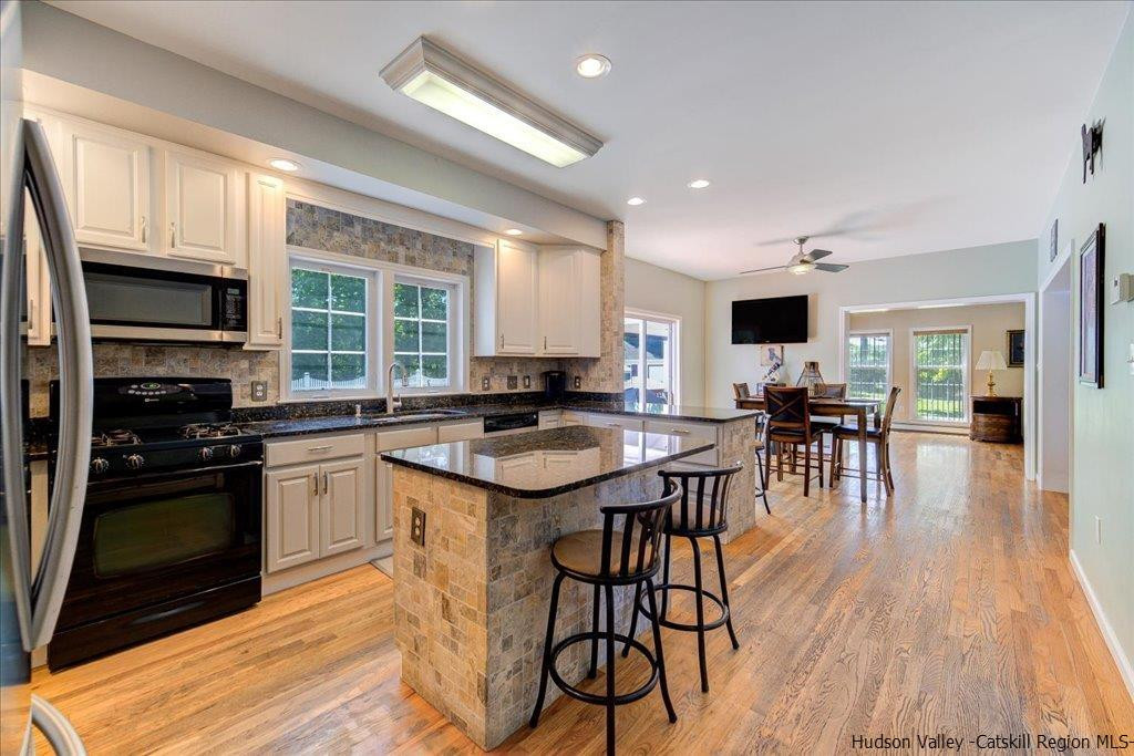 1237 Hoagerburgh Road Wallkill, NY 12589 - Photo 15 of 35 a open kitchen with stainless steel appliances granite countertop a stove top oven a sink dishwasher and white cabinets with wooden floor