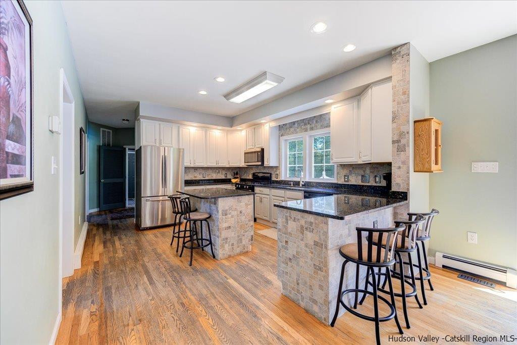 1237 Hoagerburgh Road Wallkill, NY 12589 - Photo 16 of 35 a kitchen with stainless steel appliances kitchen island granite countertop a refrigerator a stove a sink a dining table and chairs with wooden floor