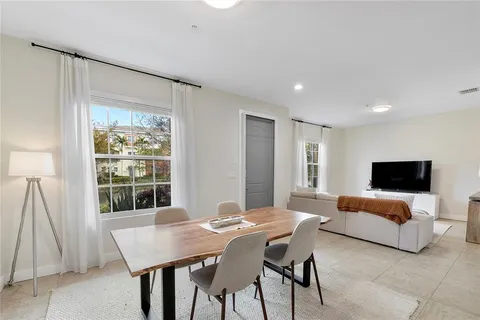 a kitchen with stainless steel appliances granite countertop a refrigerator a sink dishwasher a dining table and chairs with wooden floor