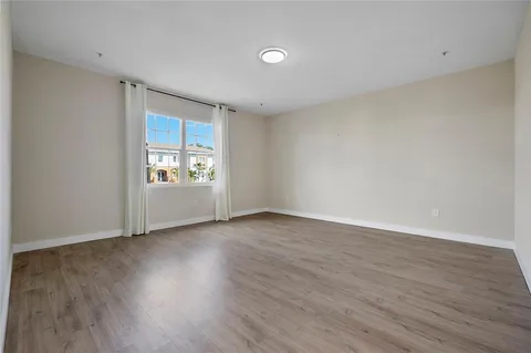 a view of an empty room with window and wooden floor