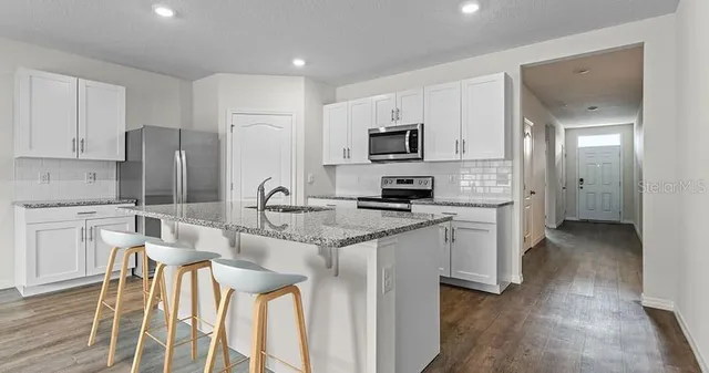 a kitchen with stainless steel appliances granite countertop a sink a microwave a refrigerator and cabinets
