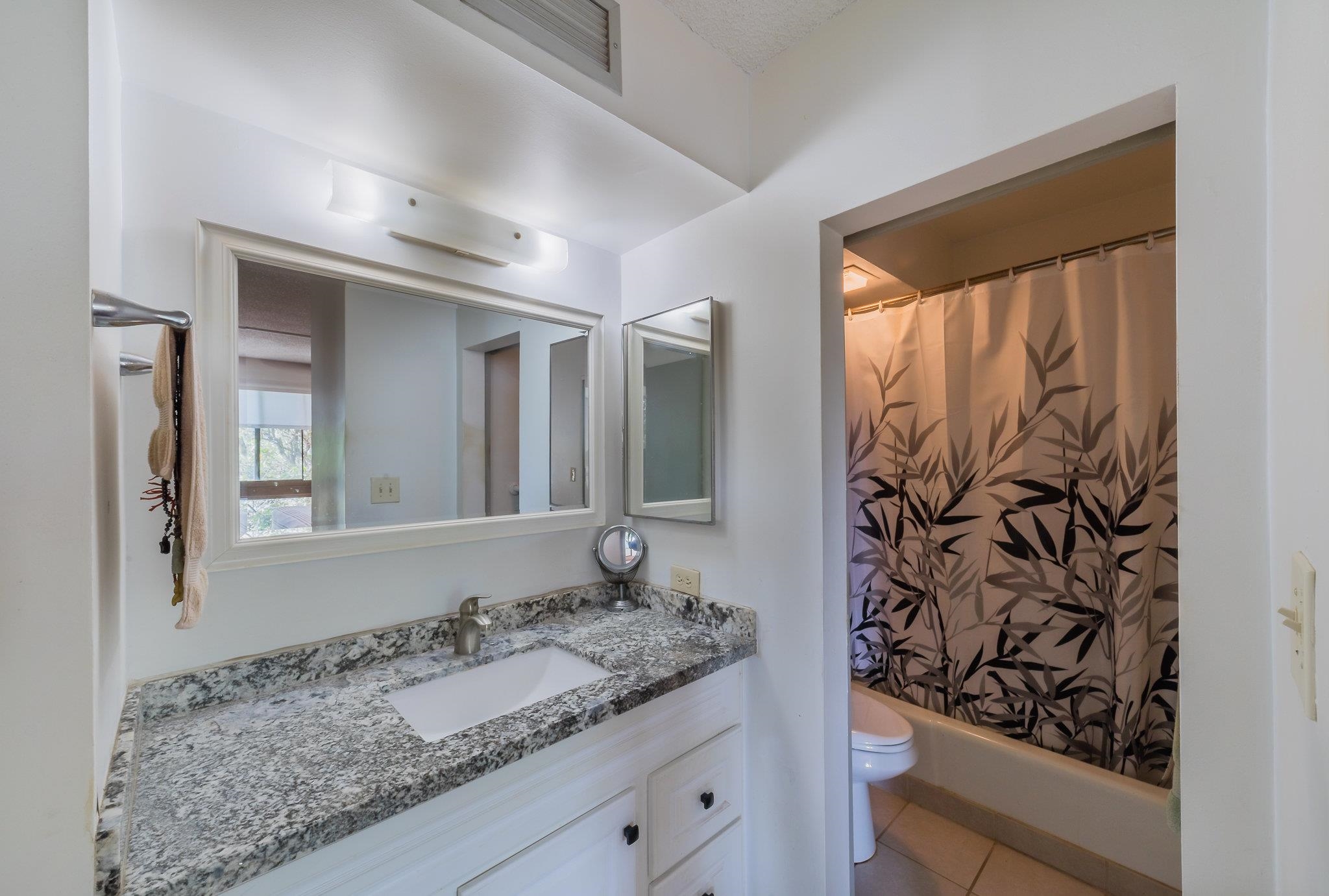 4310 Lower Honoapiilani Road, Unit 419 Lahaina, HI 96761 - Photo 20 of 32 a bathroom with a granite countertop sink and a mirror