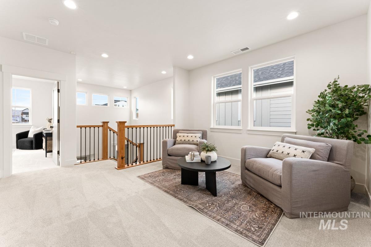 13338 North Spring Creek Way Boise, ID 83714 - Photo 15 of 46 Carpeted upper-level landing featuring a wooden staircase with black iron balusters, recessed lighting, and multiple windows providing natural illumination
