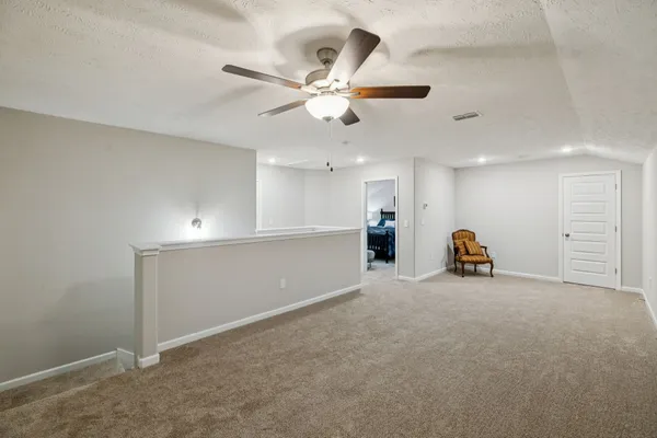 an empty room with windows and ceiling fan