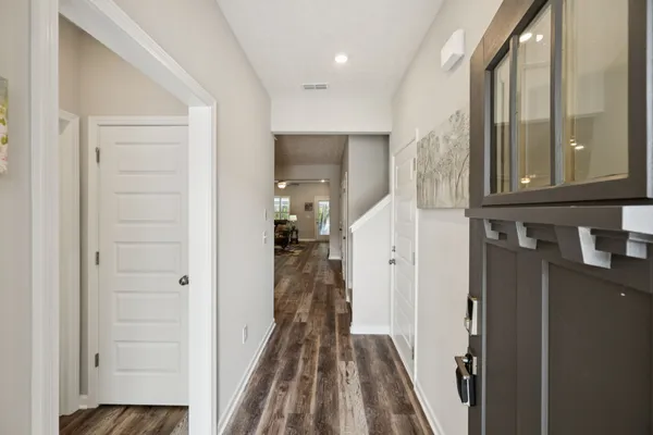 a view of a hallway with wooden floor and a bathroom