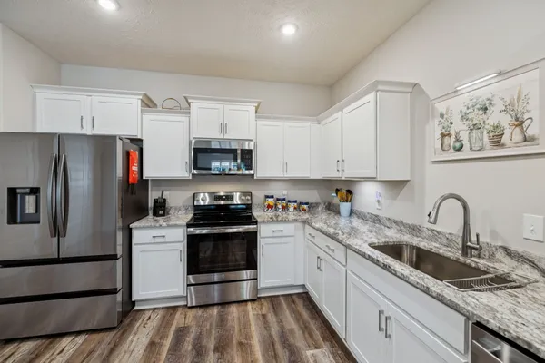 a kitchen with granite countertop white cabinets white stainless steel appliances and a granite counter tops