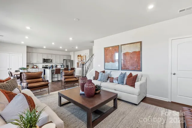 a living room with furniture kitchen view and a window