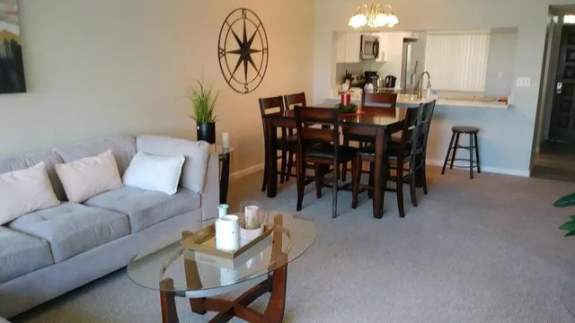 a view of a dining room and livingroom with furniture a rug a chandelier and a rug
