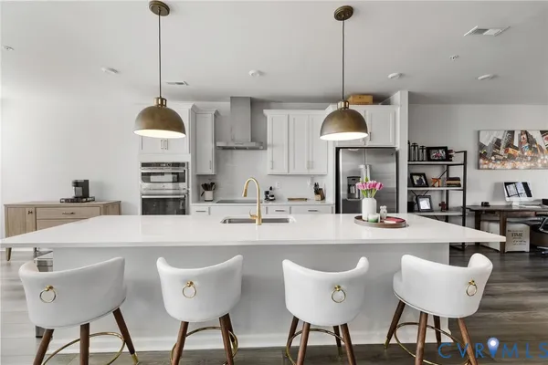 a kitchen with stainless steel appliances kitchen island granite countertop a dining table chairs and a sink