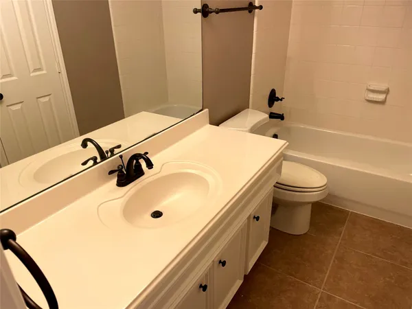 a bathroom with a granite countertop bathtub shower sink vanity and toilet