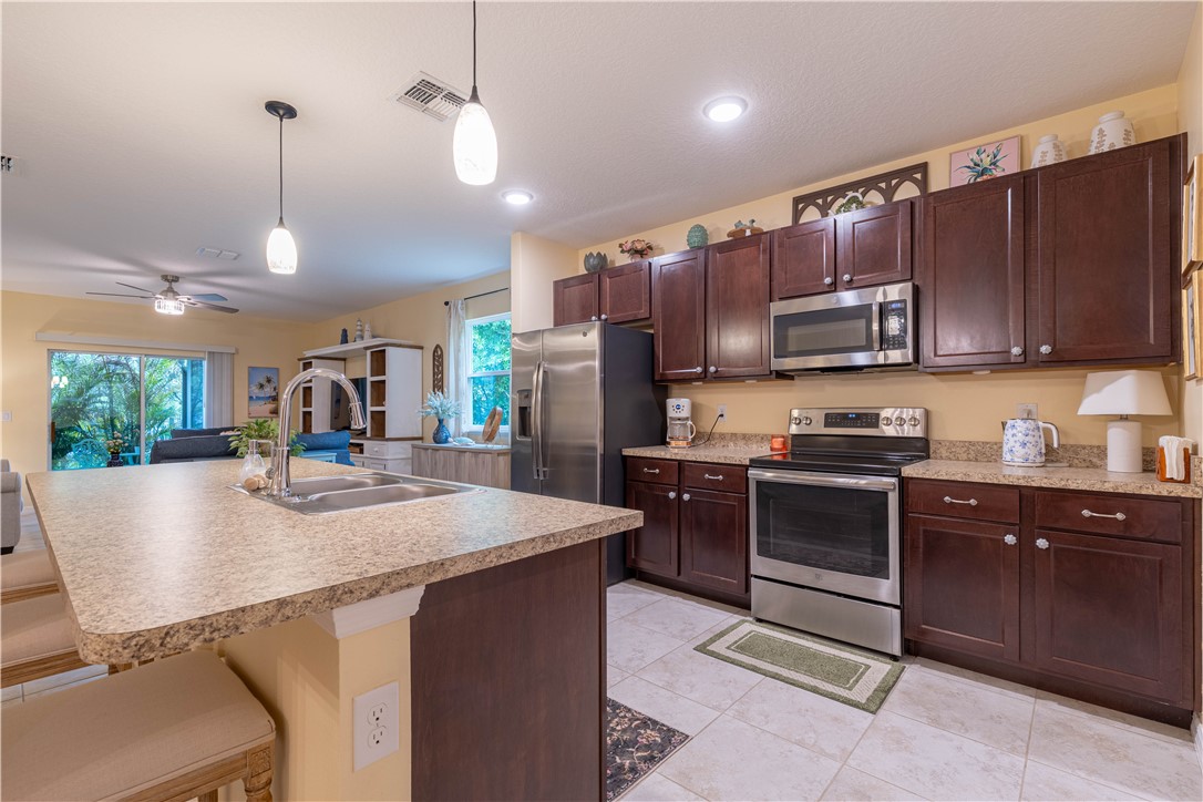 898 Lorca Avenue Sebastian, FL 32958 - Photo 16 of 36 a kitchen with kitchen island granite countertop a stove top oven a sink dishwasher a dining table and chairs with wooden floor