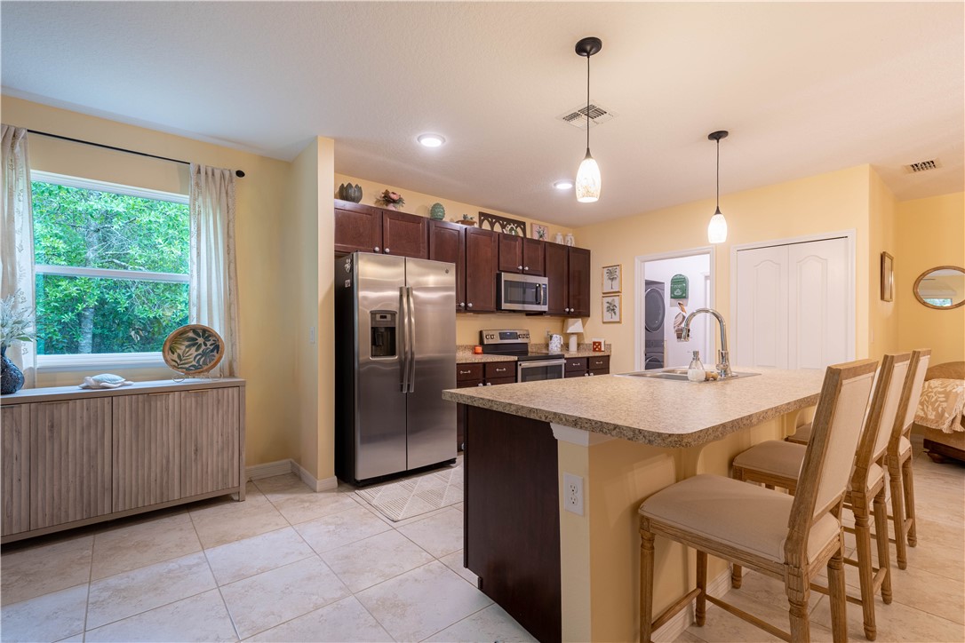 898 Lorca Avenue Sebastian, FL 32958 - Photo 19 of 36 a kitchen with stainless steel appliances kitchen island granite countertop a table chairs and a refrigerator