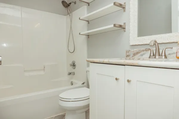 a bathroom with a granite countertop sink a toilet and shower