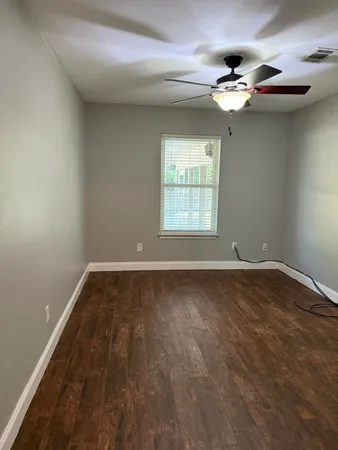 en empty room with windows and chandelier fan