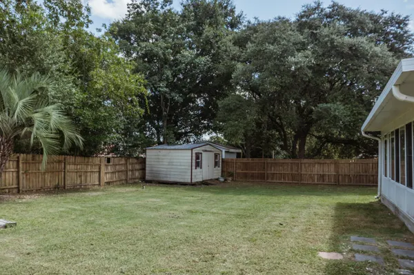 a view of a backyard with wooden fence and large trees