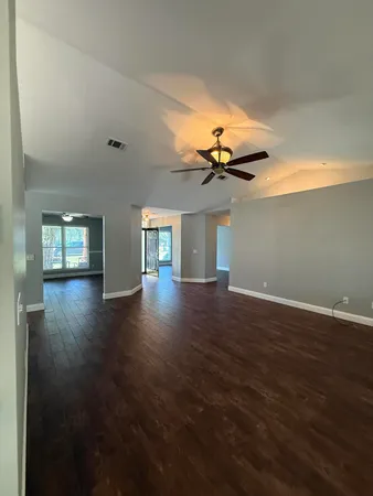 a view of empty room with wooden floor and fan