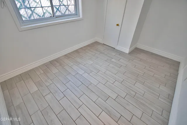 a view of a refrigerator in kitchen and an empty room