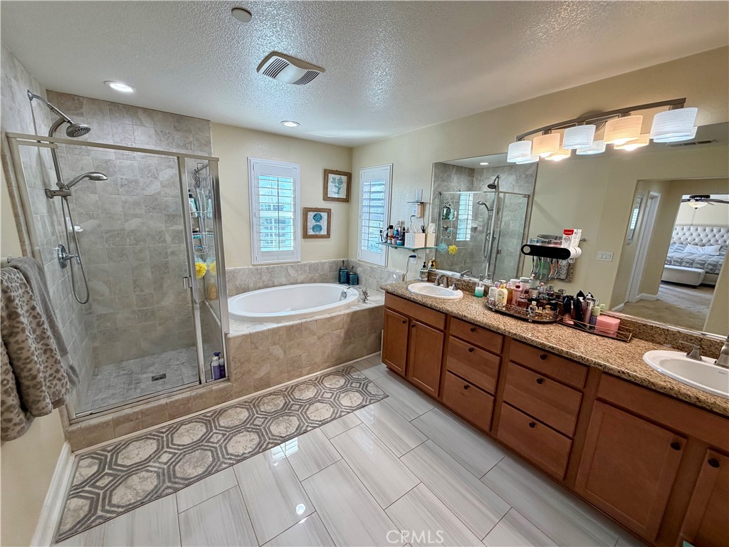 13538 Applegate Court Rancho Cucamonga, CA 91739 - Photo 15 of 30 a spacious bathroom with a double vanity sink a large mirror a bathtub and shower