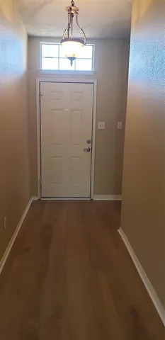 an empty room with a chandelier fan and wooden floor