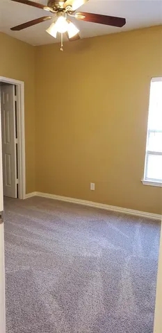 an empty room with a chandelier fan and windows