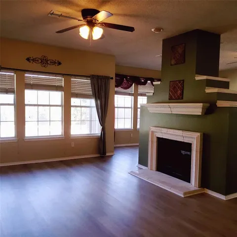 an empty room with windows fireplace and wooden floor